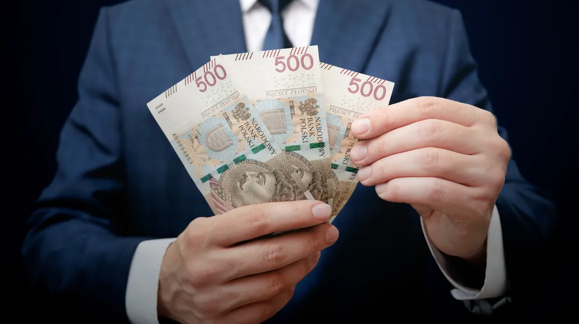 Mężczyzna w garniturze trzymający banknoty 500 zł